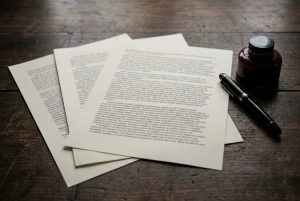Bedruckte Blätter und Füllfederhalter auf einem Holztisch